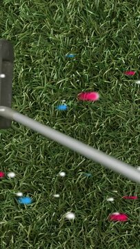 Vertical video: Putter entering right sweeping past white dimpled ball, confetti showing aim