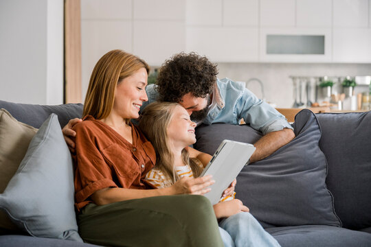 Family relaxing on sofa using digital tablet together at home