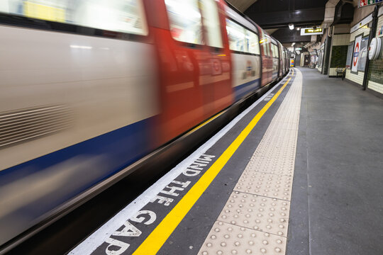 Blurred London underground train passing mind the gap sign. London, UK, 3 March 2023