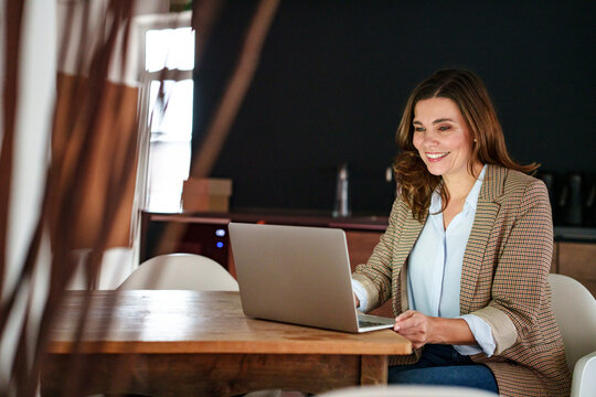 Smiling manager using laptop at desk in office