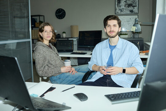 Programmers sitting at desk in office looking at camera