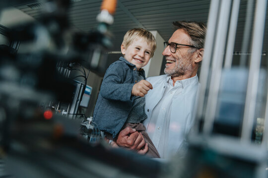 Scientist with child smiling in laboratory near research equipment