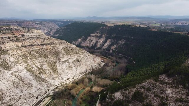 High-altitude 4K drone panorama of the J&uacute;car River valley and the Spanish plateau. Wide aerial shot featuring dense pine forests, white limestone escarpments, and distant horizons in Castilla-La Manch