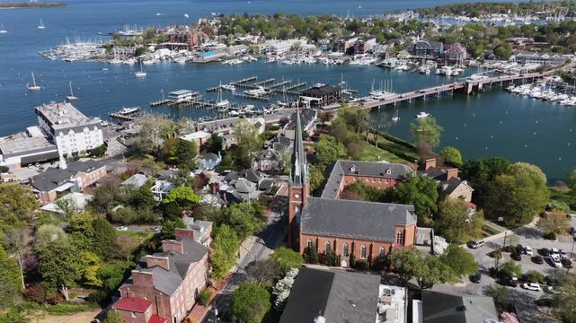 Aerial view of Annapolis, Maryland, USA with church steeple, marina and waterfront bridge, surrounded by historic homes and boats in bright spring sunlight along scenic Chesapeake Bay. Wide shot.