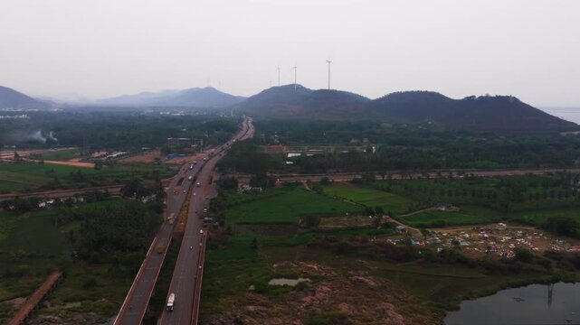 National highway with mountains, crop field lands, Wind Turbines and Tungabhadra reservoir at Hosapete, Karnataka, india. day time, circle shot, drone shot, 4k.