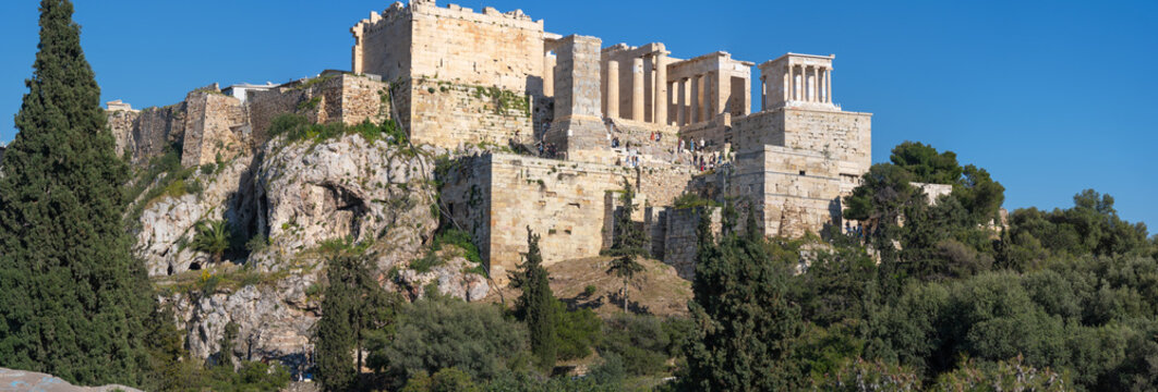 A ground-level view of the monumental entrance to the Acropolis, showing the Propylaea and Temple of Athena Nike among ancient fortifications.