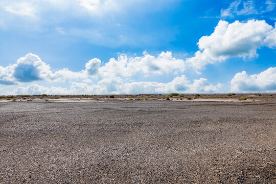 Vast sand plain under blue sky with white cumulus clouds in Xinjiang, China