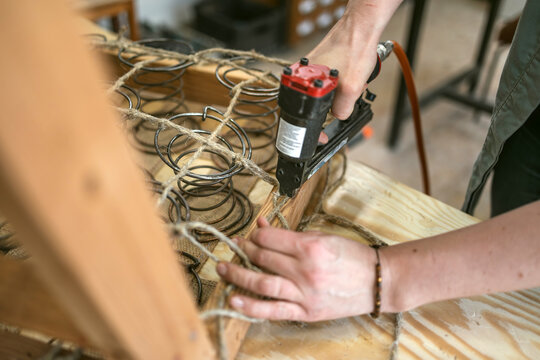 Craftswoman Attaching Upholstery Springs with Staple Gun
