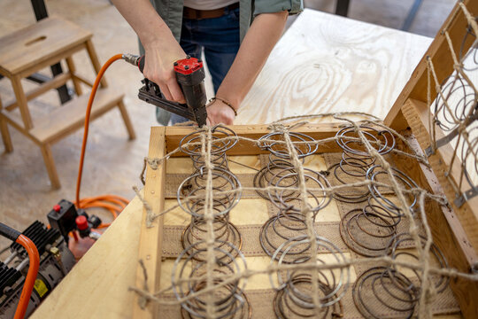 Craftswoman Attaching Upholstery Springs with Staple Gun

