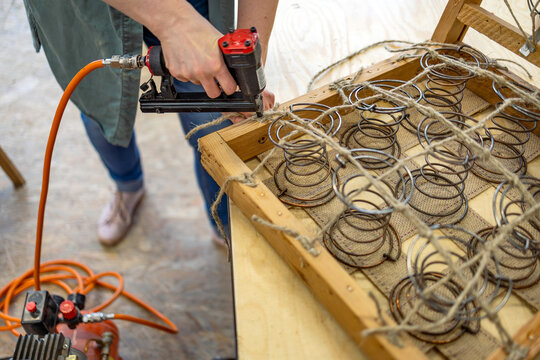Craftswoman Attaching Upholstery Springs with Staple Gun
