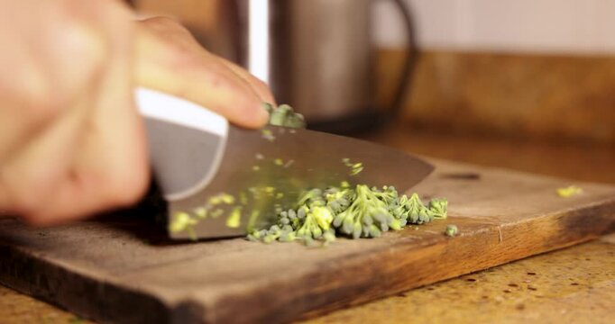 Chef chopping fresh broccolini on wooden board