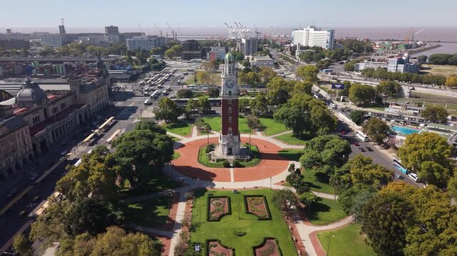 Cinematic drone shot moving forward toward the Torre Monumental clock tower in Plaza Fuerza A&eacute;rea Argentina, featuring the Retiro train station