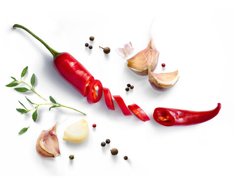 Fresh red chili pepper whole and sliced with garlic cloves, herb sprig, and peppercorns isolated on transparent background with photorealistic transparent shadow