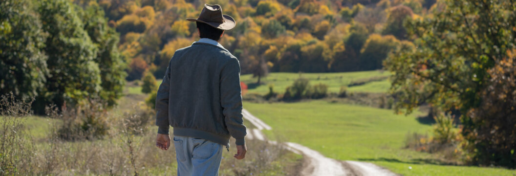 Man standing at the edge of a valley road, observing the scenic landscape ahead, reflecting contemplation, adventure, and connection with nature.