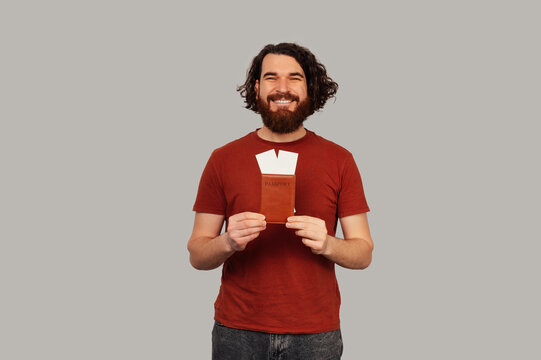 White Man Smiling Holding Vacation tickets and passport.