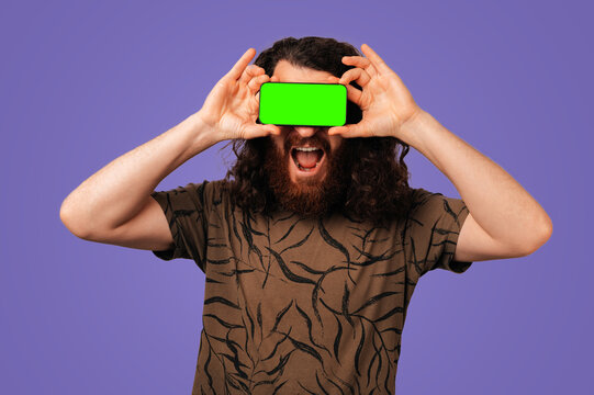 White Man Holding Green Viewfinder, Ecstatic Expression With Beard And Long Hair, Studio Purple Background,