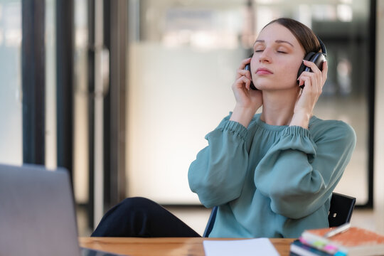 Young woman relaxing with headphones at desk, taking a break from work, stress relief and mental health concept.