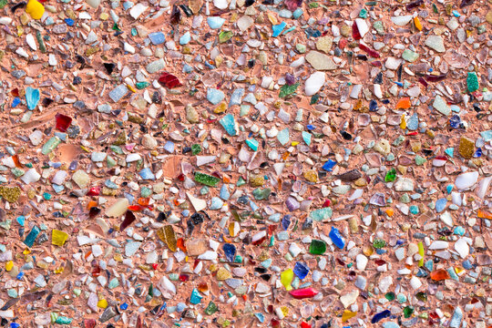 Colorful pieces of glass and stone create a mosaic pattern on a surface during a sunny day in a public area