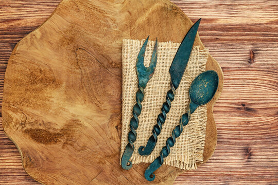 Vintage utensils on a wooden board with natural texture and a woven mat underneath