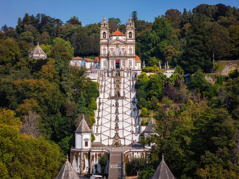 Aerial view of Bom Jesus do Monte in Braga, Portugal. The image shows the sanctuary, church, and the long staircase surrounded by trees. This landmark is a major site for visitors.