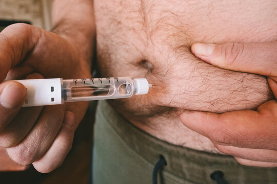 Overweight man injecting pen with GLP-1 medicine into his belly. Semaglutide, Ozempic, Tirzepatide or insulin drug against fat. Modern weight loss treatment, diabetes therapy and obesity management