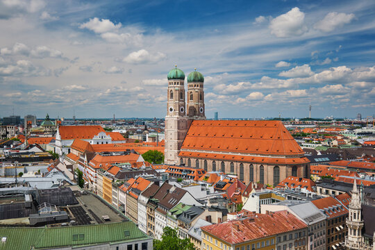 Wide angle aerial view of the iconic Frauenkirche towers and Munich city center architecture under a blue sky in Bavaria, Germany.