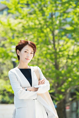 Fototapeta premium 新緑の並木道を歩く30代ビジネス女性