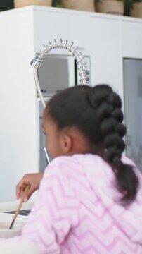 Vertical video: Kid pink hoodie reaching for bowl, stirring in kitchen with spoon, copy space
