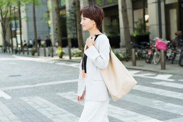 Fototapeta premium 新緑の並木道を歩く30代ビジネス女性