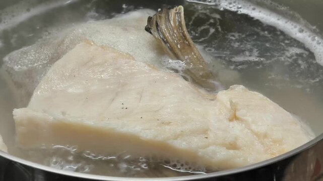 boiling cod fish in water in iron pot