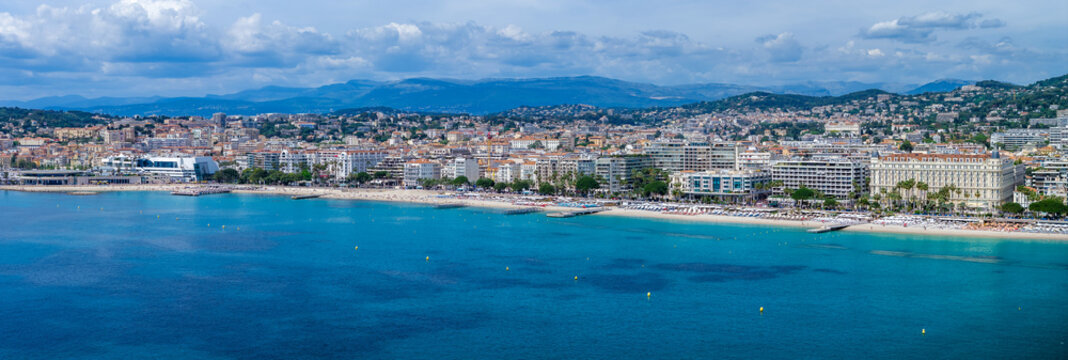 A wide aerial view shows the Cannes waterfront in France, the Bay of Cannes, the Palais des Festivals et des Congres, and Carlton Cannes along the Croisette.