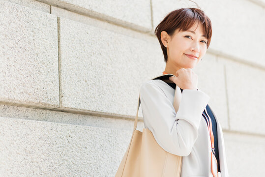 石造りの建物の前を歩く30代ビジネス女性