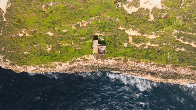 Coastal Erosion, Cinematic drone flight over the rugged eroding edge of Dingli Cliffs in Malta, showing contrast between green plateau and deep blue mediterranean sea.