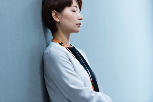 オフィスの壁に寄りかかる30代ビジネス女性