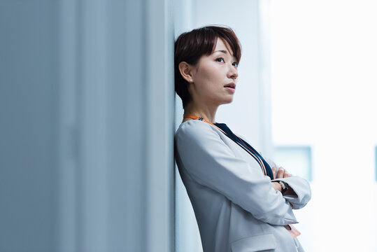 オフィスの壁に寄りかかる30代ビジネス女性