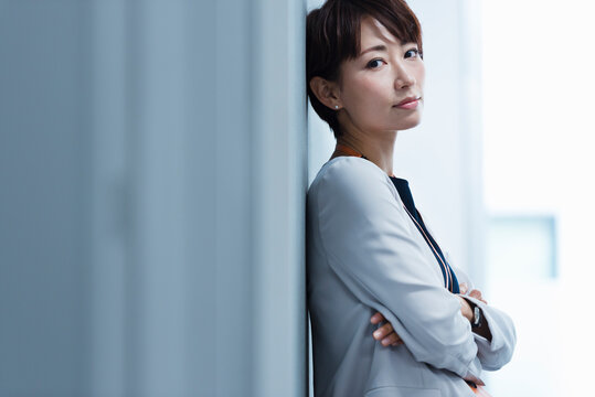 オフィスの壁に寄りかかる30代ビジネス女性