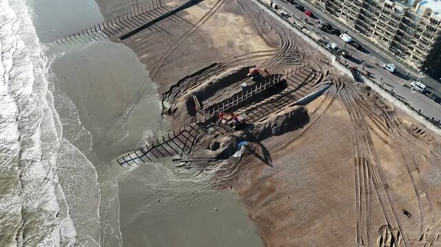 4K aerial drone footage of Hove seafront beach replenishment works. New wooden groynes under construction as shingle is added to widen the beach along Brighton and Hove's sunny Sussex coastline.