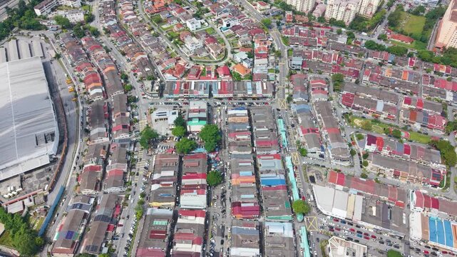 Push in drone shot of Cheras district market street in Kuala Lumpur, Malaysia. Dense urban layout with colorful rooftops, street activity, and a local commercial area.