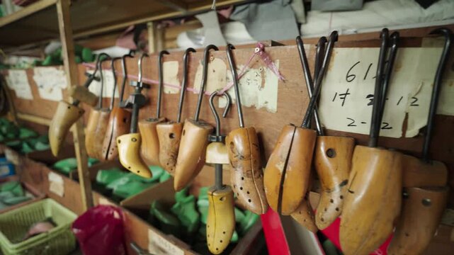 Wooden shoe molds hanging in a workshop in Malaysia. Traditional tools used for shaping footwear highlight craftsmanship, heritage techniques, and artisan production environment.