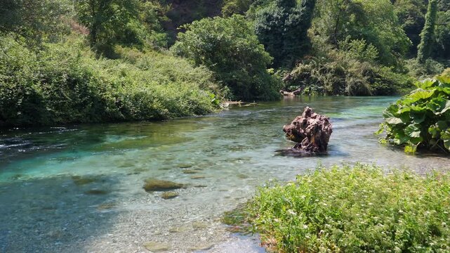 Crystal clear water of the Bistrice river flowing from the Blue Eye spring in Albania, a popular travel destination surrounded by green nature