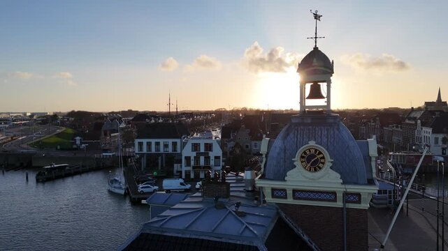 Static aerial close view of the old harbormaster tower with clock and bell at dawn.