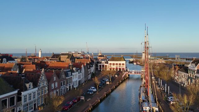 Drone lifts from the ship and canal toward the sea horizon in warm morning light.