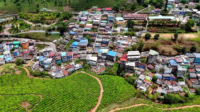 Drone shot capturing Valparai with dense housing clusters, curving streets, and adjacent tea estates, blending urban life seamlessly with scenic plantation landscapes.