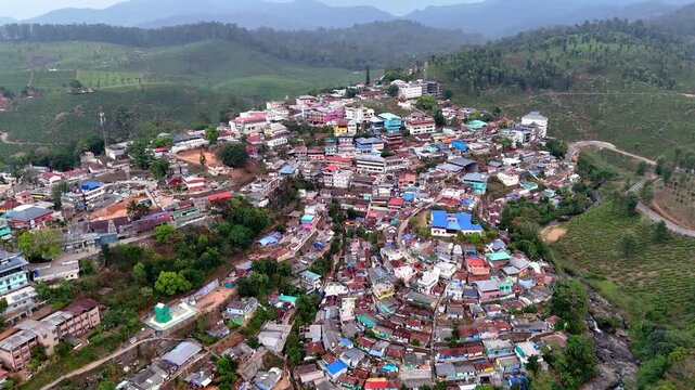 Wide cinematic aerial of Valparai highlighting textured tea gardens, a serpentine trail, and a compact settlement blending into dense forest cover and rolling hills.