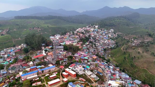 Wide cinematic aerial of Kodaikanal highlighting layered hills, clustered homes, curving roads, and lush landscapes, creating a picturesque tourist hill station atmosphere.