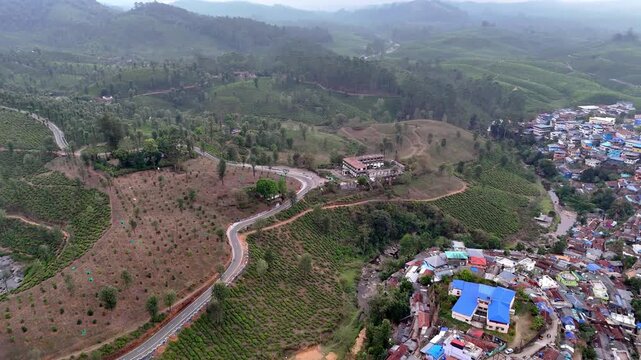 Drone shot capturing the scenic charm of Kodaikanal with compact urban layout, hillside buildings, open grounds, and surrounding greenery blending into misty mountain terrain.