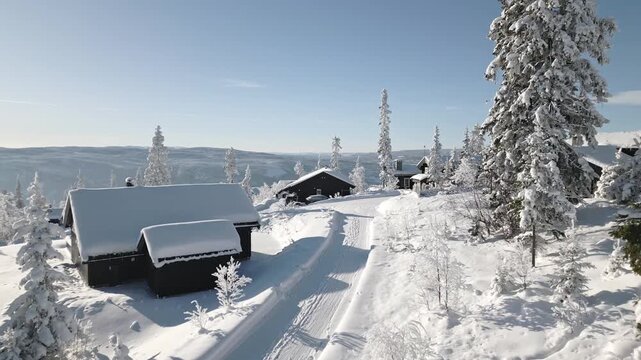 Aerial glide past snowy cabin retreat in Danebu, Valdres, Norway with frosted alpine trees and snow covered road on a clear winter day