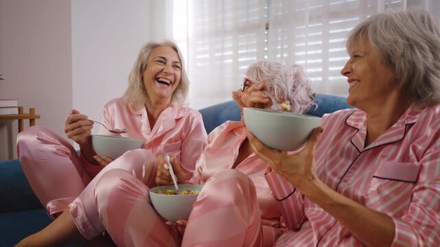 Beautiful senior women having funny pajama party at home - Group of cheerful elderly female friends having fun at home, concepts about old people, lifestyle and quality of life	
