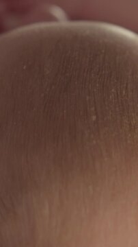 Extreme close-up reveals delicate skin texture and fine hair on a newborn's head, showcasing natural details
