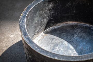 Fototapeta premium Solar oven outdoor cooking with large black metal pot placed on concrete surface showing signs of use and wear suitable for sustainable food preparation